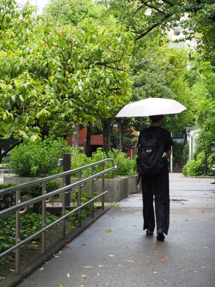 小雨の中を傘を差して歩く様子